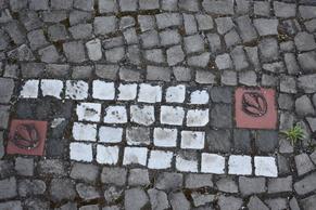 Kachelmosaike in weiß, roten kleinen Gehwegsteinen.