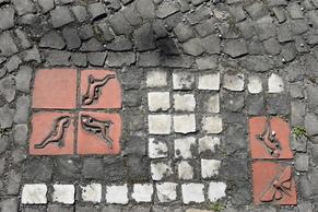 Kachelmosaike in weiß, roten kleinen Gehwegsteinen.