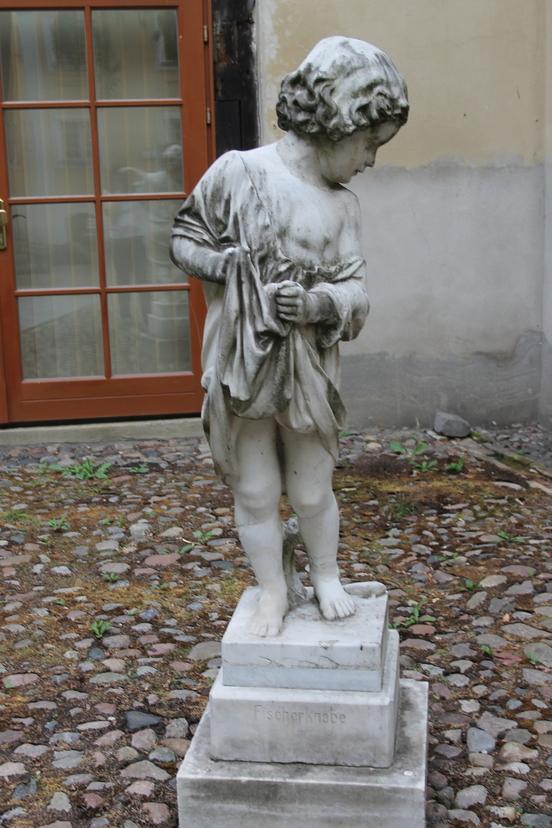 Weiße Skulptur eines jungen Knaben.