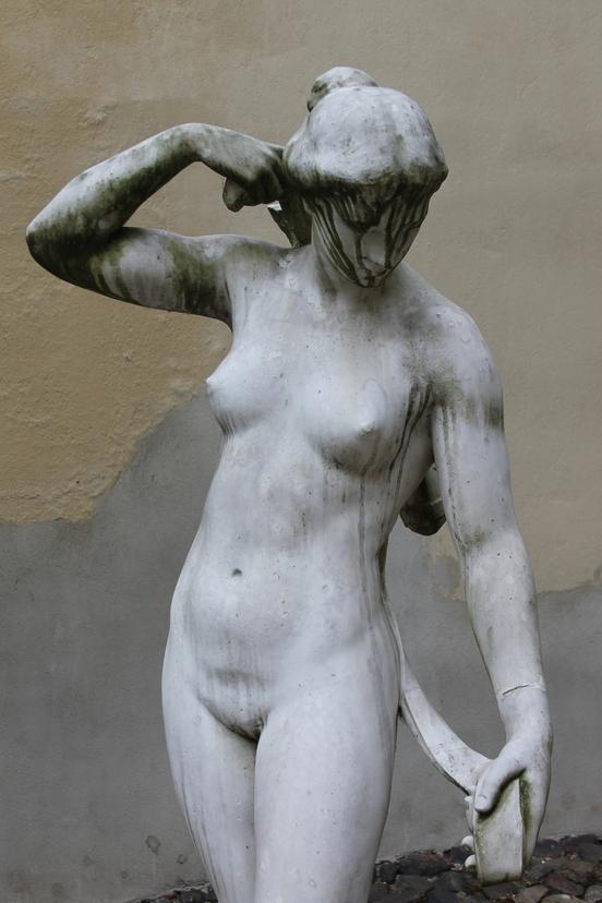 Foto der Skulptur Diana, die ein Tuch am Rücken mit beiden Armen hält.