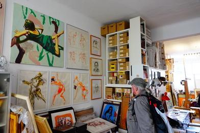 Bild eines Ateliers mit einer Wand, vollgehängt mit Kunstwerken.