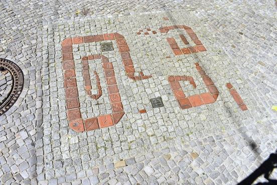 Bodenmosaik aus ziegelroten Gehwegsteinen.