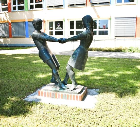 Tanzende Kinder vor einer Schule