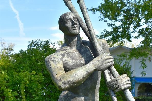 Stehender Ruderer, der zwei Ruder in der Hand trägt