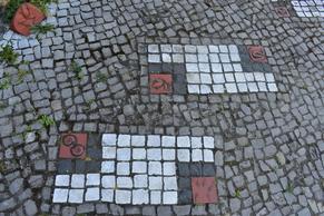 Kachelmosaike in weiß, roten kleinen Gehwegsteinen.