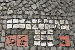 Kachelmosaike in weiß, roten kleinen Gehwegsteinen.