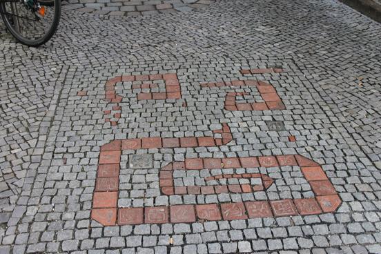 Bodenmosaik aus ziegelroten Gehwegsteinen.